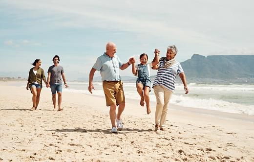 Une adorable petite fille s'amusant à la plage avec ses parents et grands-parents