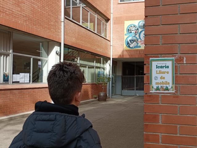 Un jeune entrant dans une école avec un panneau indiquant zone sans téléphone.